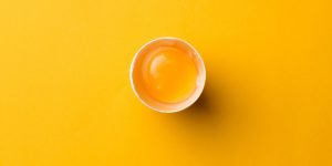 White egg and egg yolk on the yellow background. topview